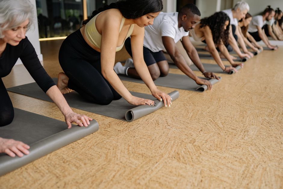 Rolled yoga mats resting on a sunlit wood floor